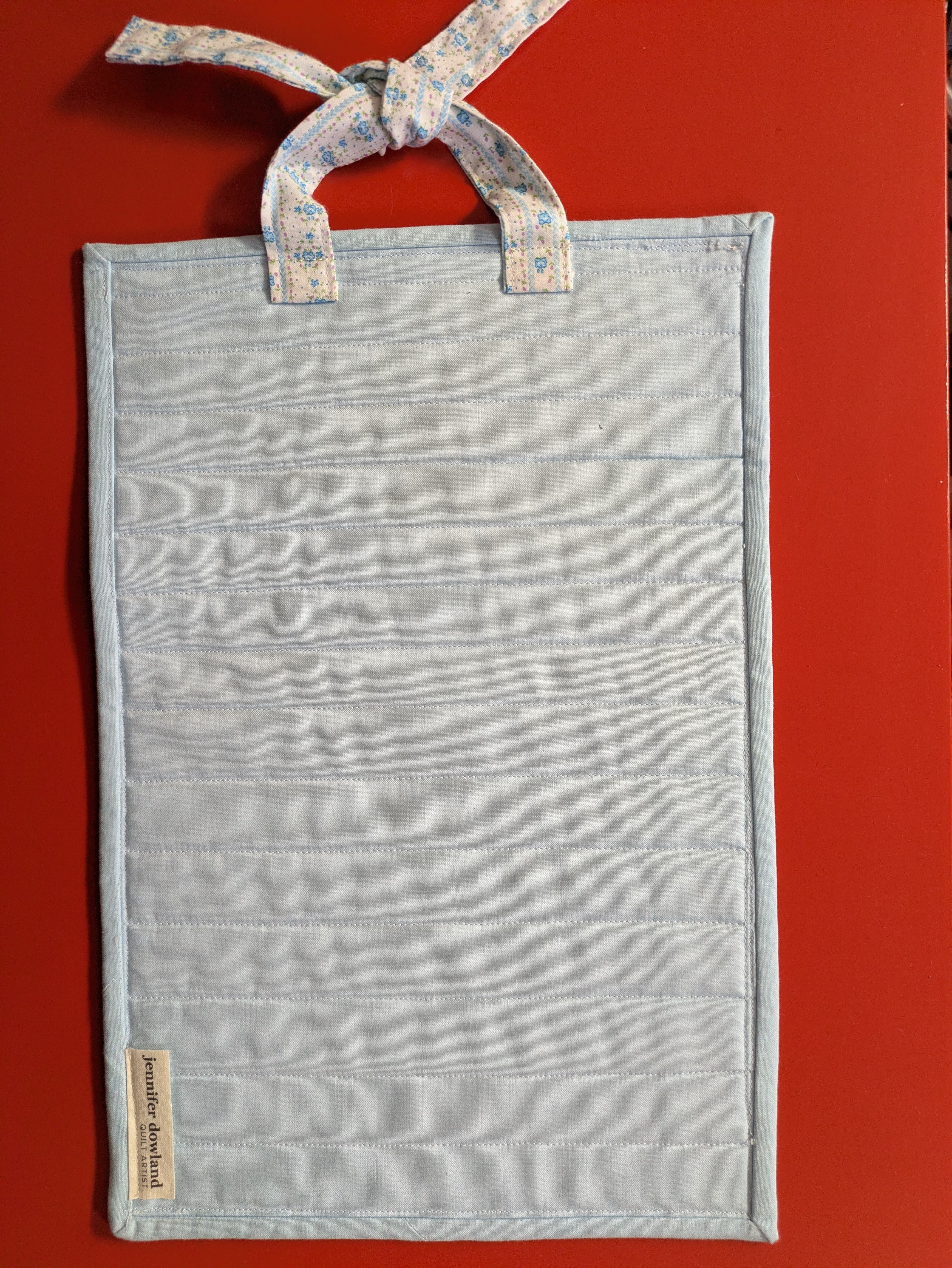 Light blue hanging quilt with floral ribbon 