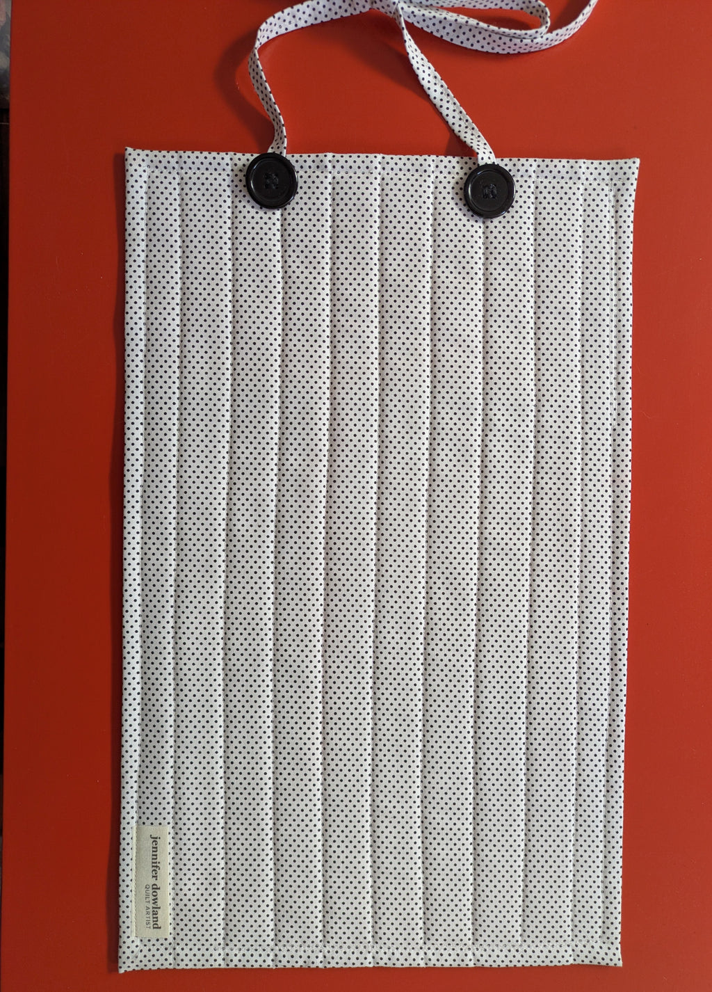 White pleated face mask with black buttons on a red background