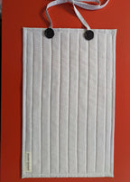White pleated face mask with black buttons on a red background