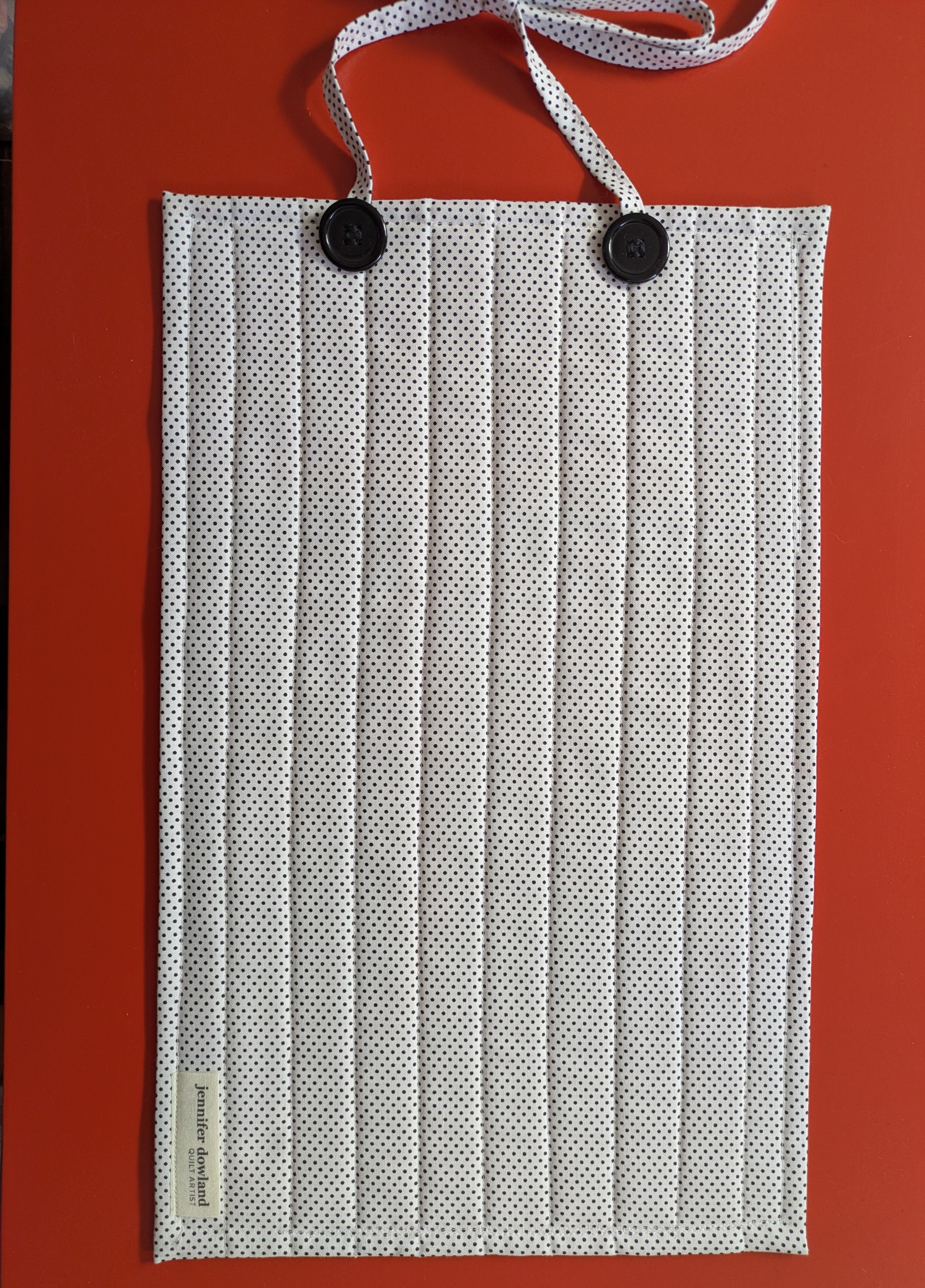 White pleated face mask with black buttons on a red background