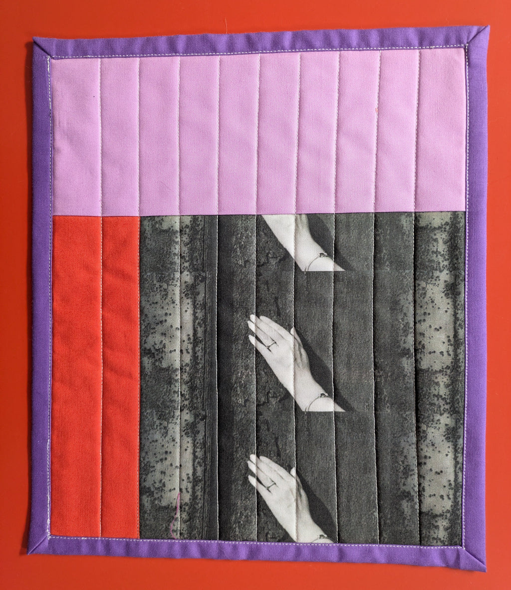 Quilt with hands and red square on a red background