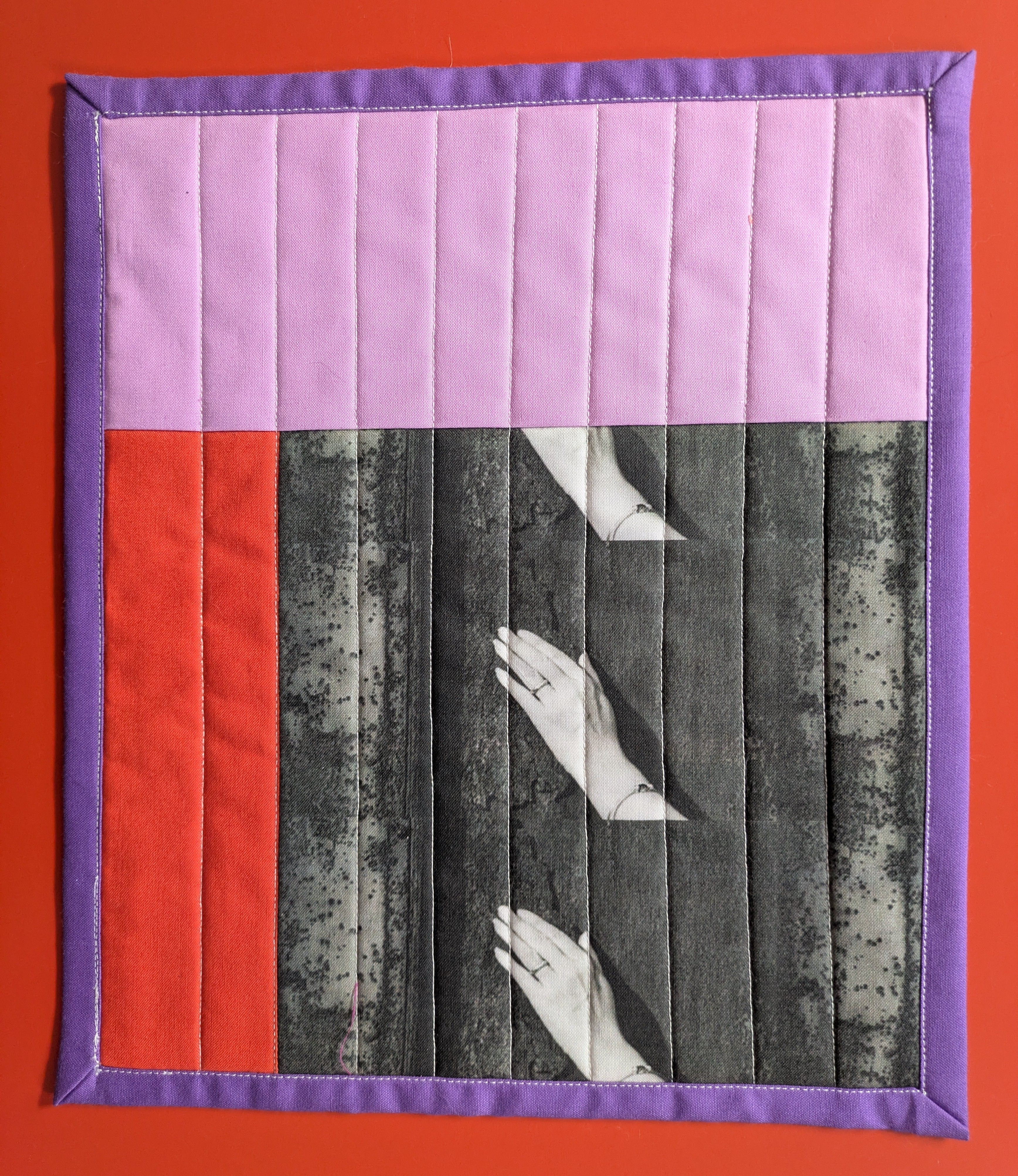 Quilt with hands and red square on a red background