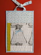 Fabric wall hanging with a pillow tick pattern  and a yellow binding and ties
