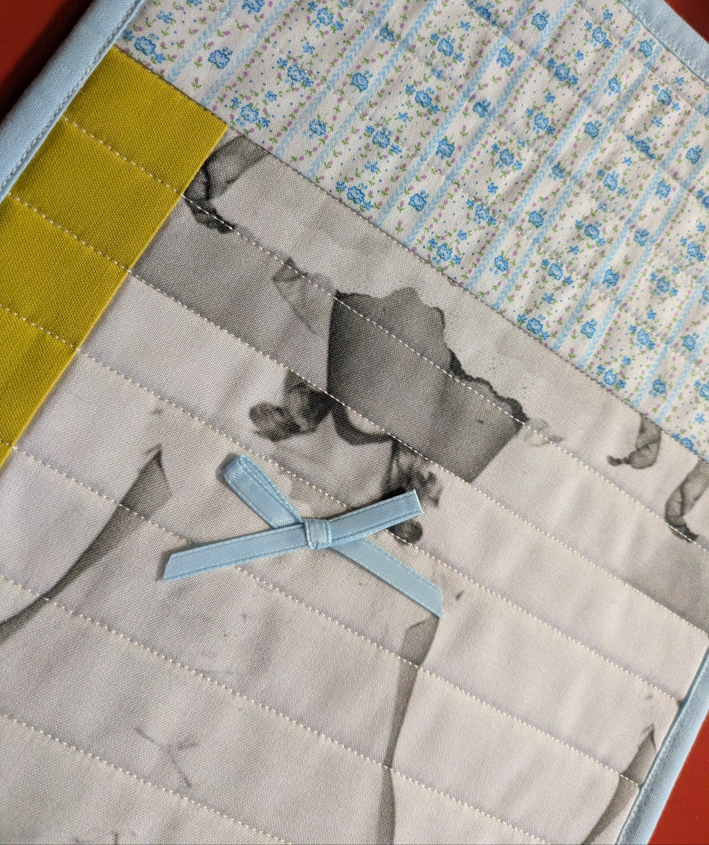 Quilt with fabric patchwork featuring a bow and printed patterns