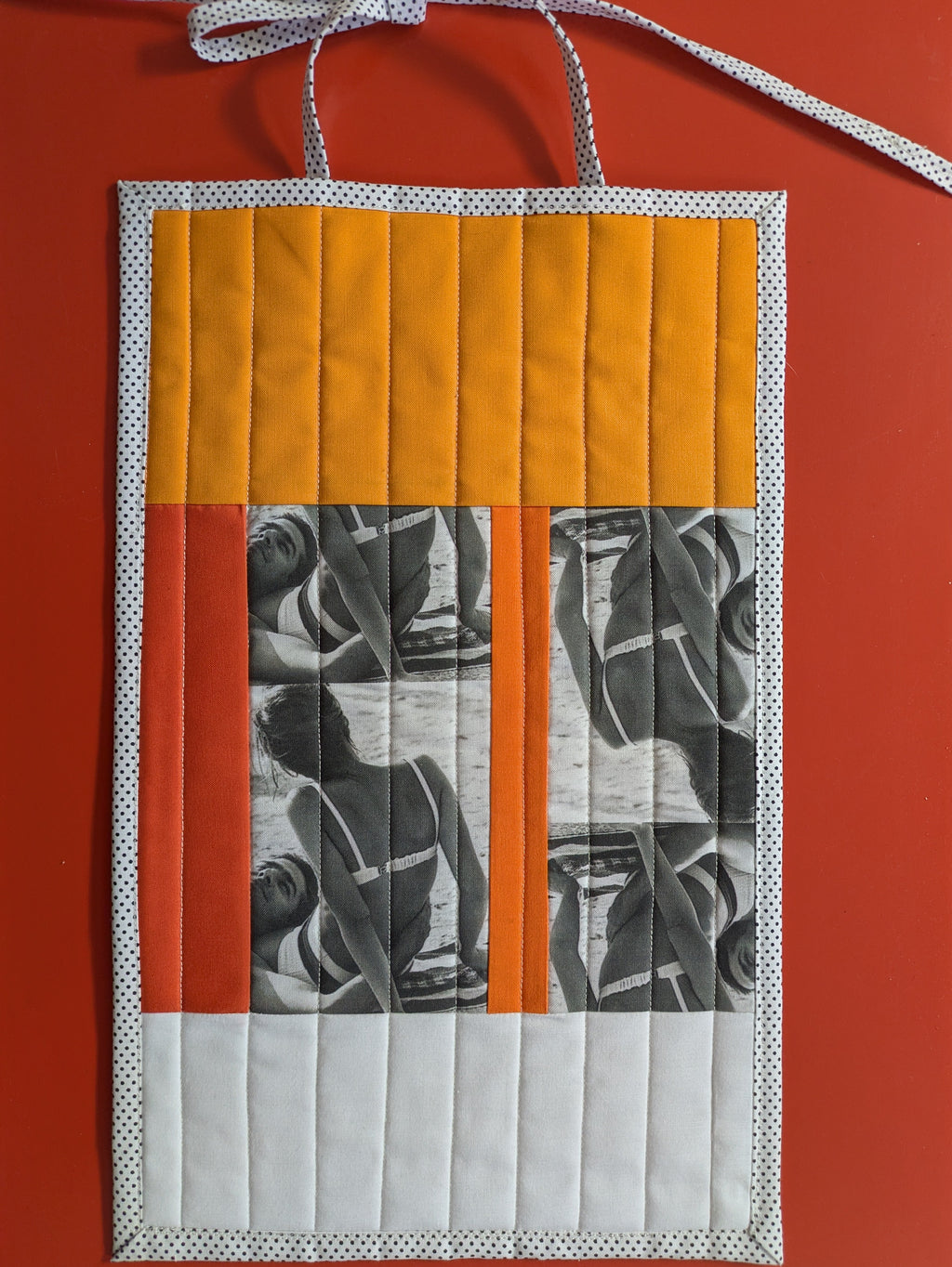 Quilted wall hanging with geometric pattern on a red background