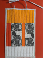 Quilted wall hanging with geometric pattern on a red background